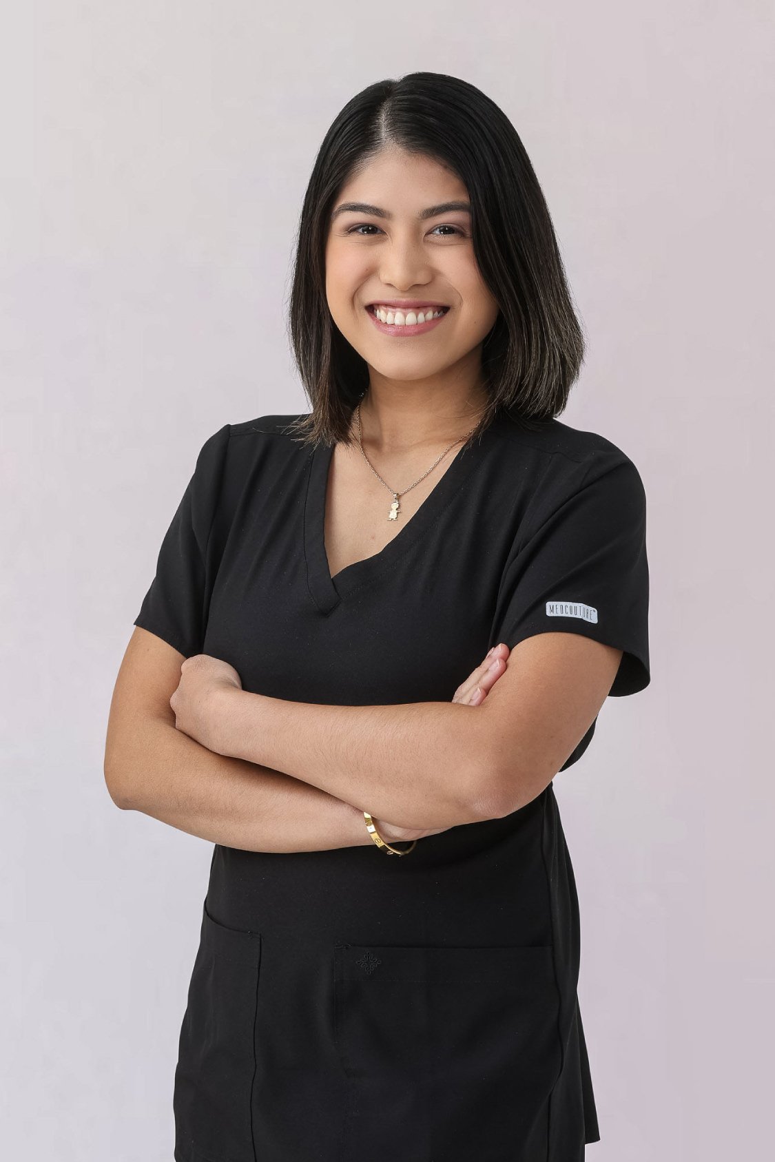 Smiling female nurse practitioner in black scrubs, arms crossed, showcasing professionalism and approachability, relevant to Thrive Medicine Clinic's focus on personalized patient care.