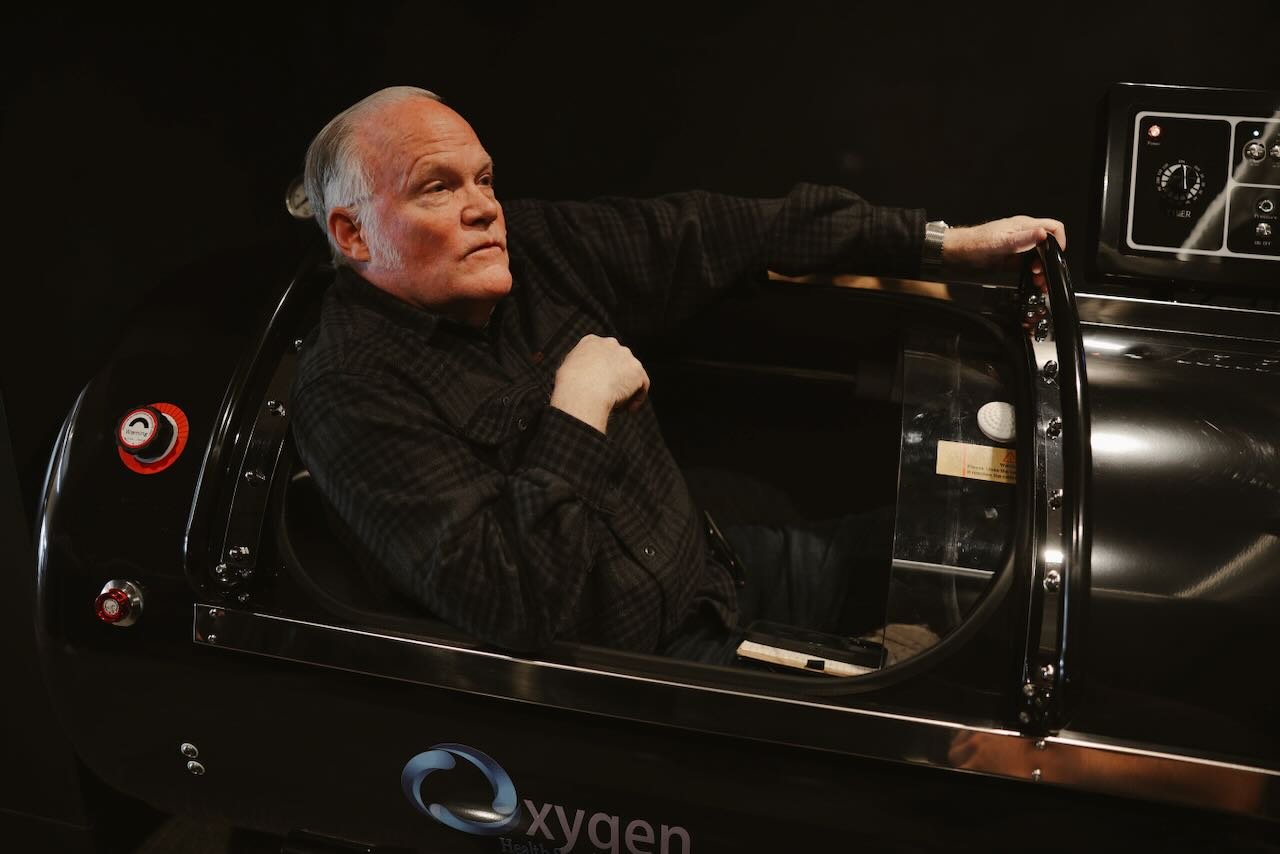 Man relaxing inside a hyperbaric oxygen therapy chamber, emphasizing a wellness-focused experience at Thrive Medicine Clinic.