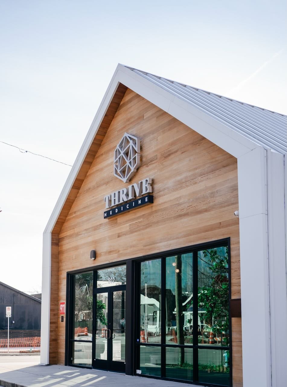 Thrive Medicine Clinic exterior featuring modern architecture, wooden facade, and prominent signage for non-surgical penile enhancement treatments.