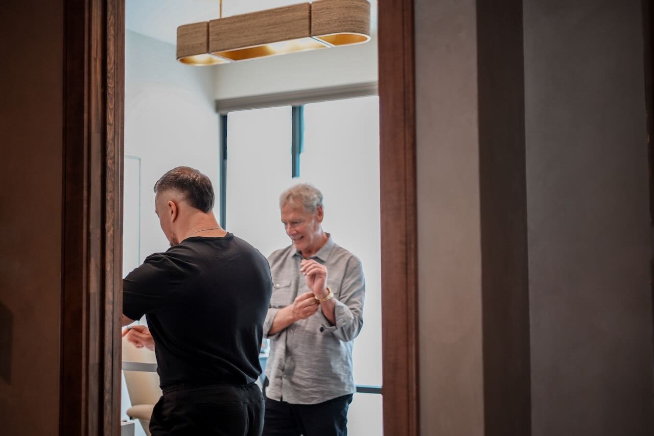 Two men interacting in a consultation setting, one in a black shirt and the other in a light gray shirt, discussing non-surgical penile enhancement options related to the P-Long Protocol at Thrive Medicine Clinic.