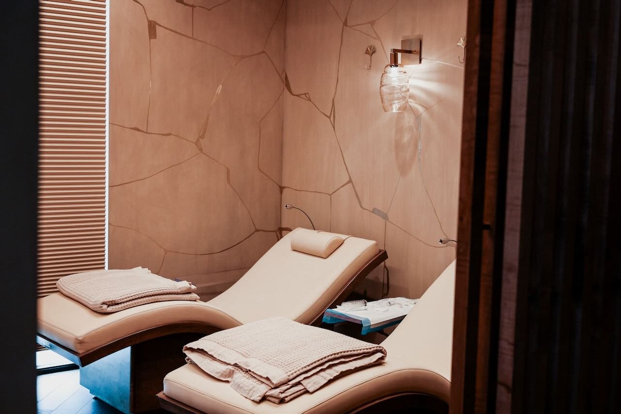 Spa treatment room with two reclining chairs, warm lighting, and neatly folded towels, reflecting a serene environment for penile enhancement therapies like hyaluronic acid fillers and PRP.