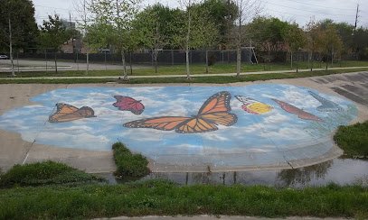 Colorful butterfly mural on pavement with blue sky background, located in Houston Heights, symbolizing community wellness and creativity.