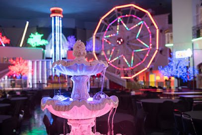 Fountain with flowing water in vibrant indoor amusement space featuring a colorful Ferris wheel and illuminated trees, representing entertainment options in Houston Heights.
