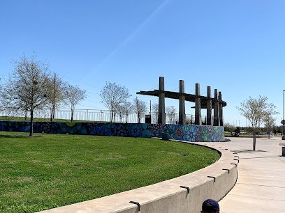 Scenic view of a landscaped park featuring a colorful mural, open green space, and a modern structure, highlighting outdoor wellness and community areas in Sugar Land.