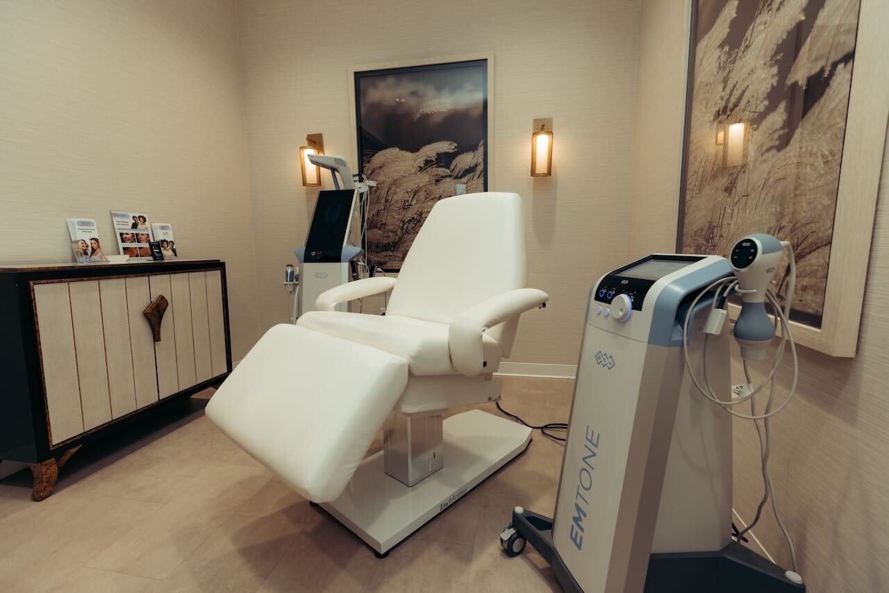 A modern treatment room at Thrive Medicine Clinic featuring a BTL Emsculpt NEO device positioned on a reclining chair, its applicator placed on a woman&rsquo;s abdomen