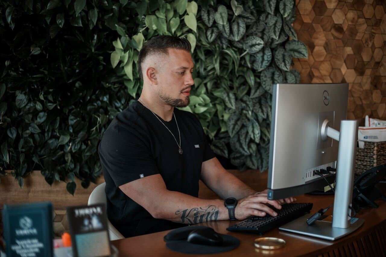 Man in his late 40s to 60s consults with a physician in a modern, private room. Both appear relaxed and engaged, reviewing information on a tablet. The setting is warm and confidential, emphasizing supportive discussion about erectile dysfunction solutions.
